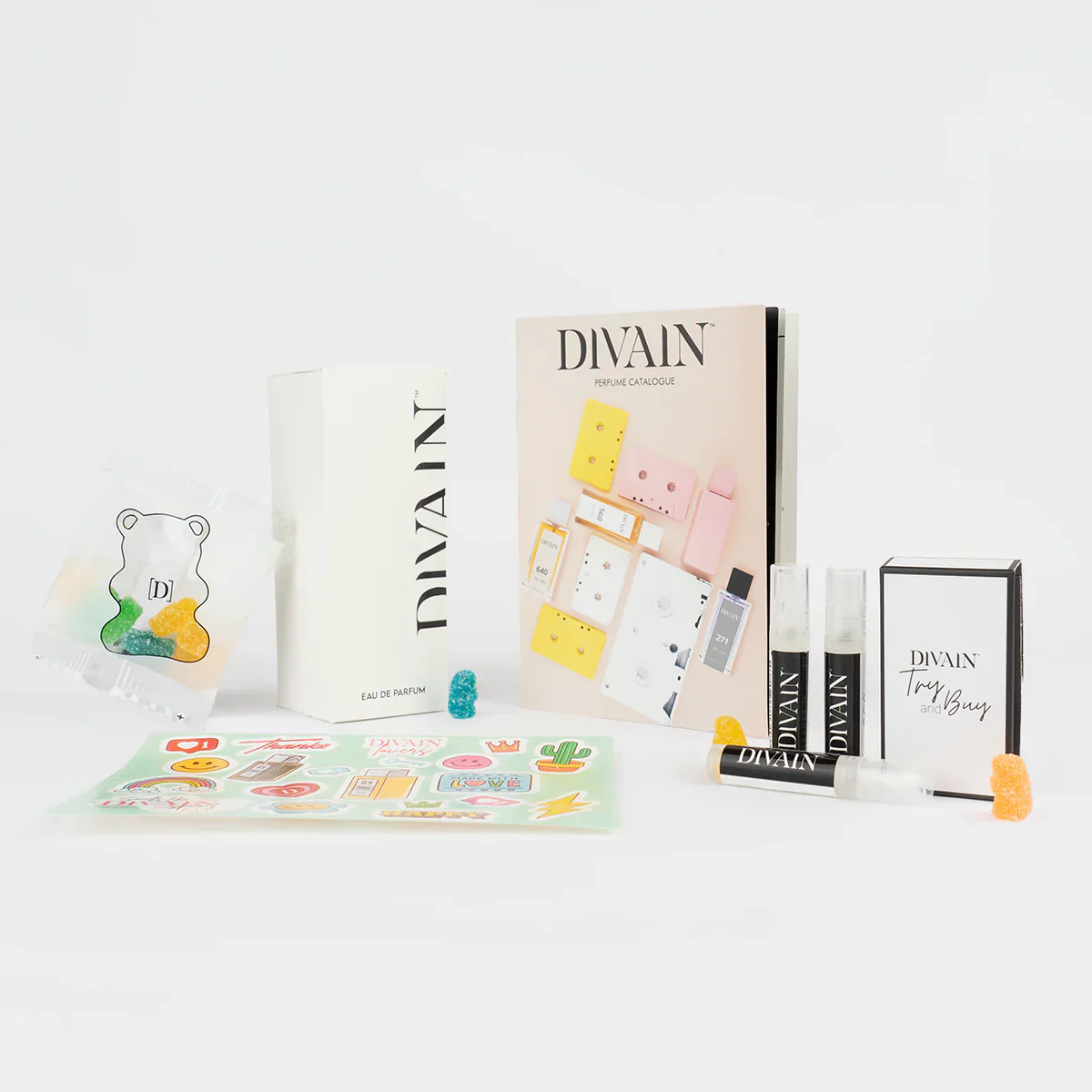 Paquet divain ouvert contenant le parfum divain-174, autocollants et bonbons
