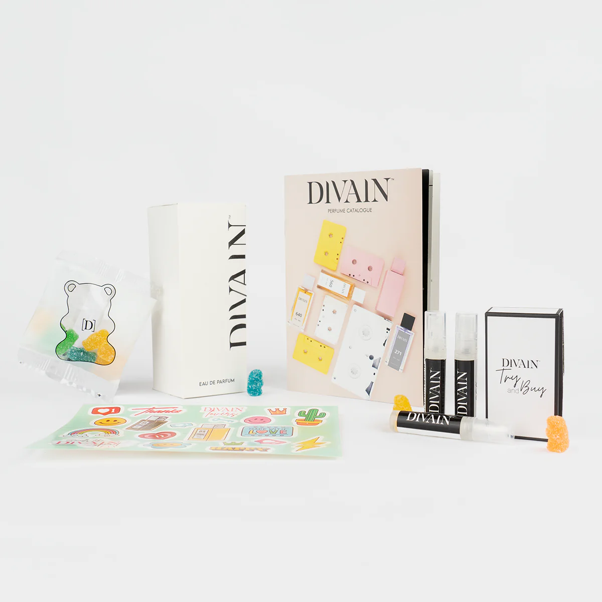 Paquet divain ouvert contenant le parfum divain-992, autocollants et bonbons
