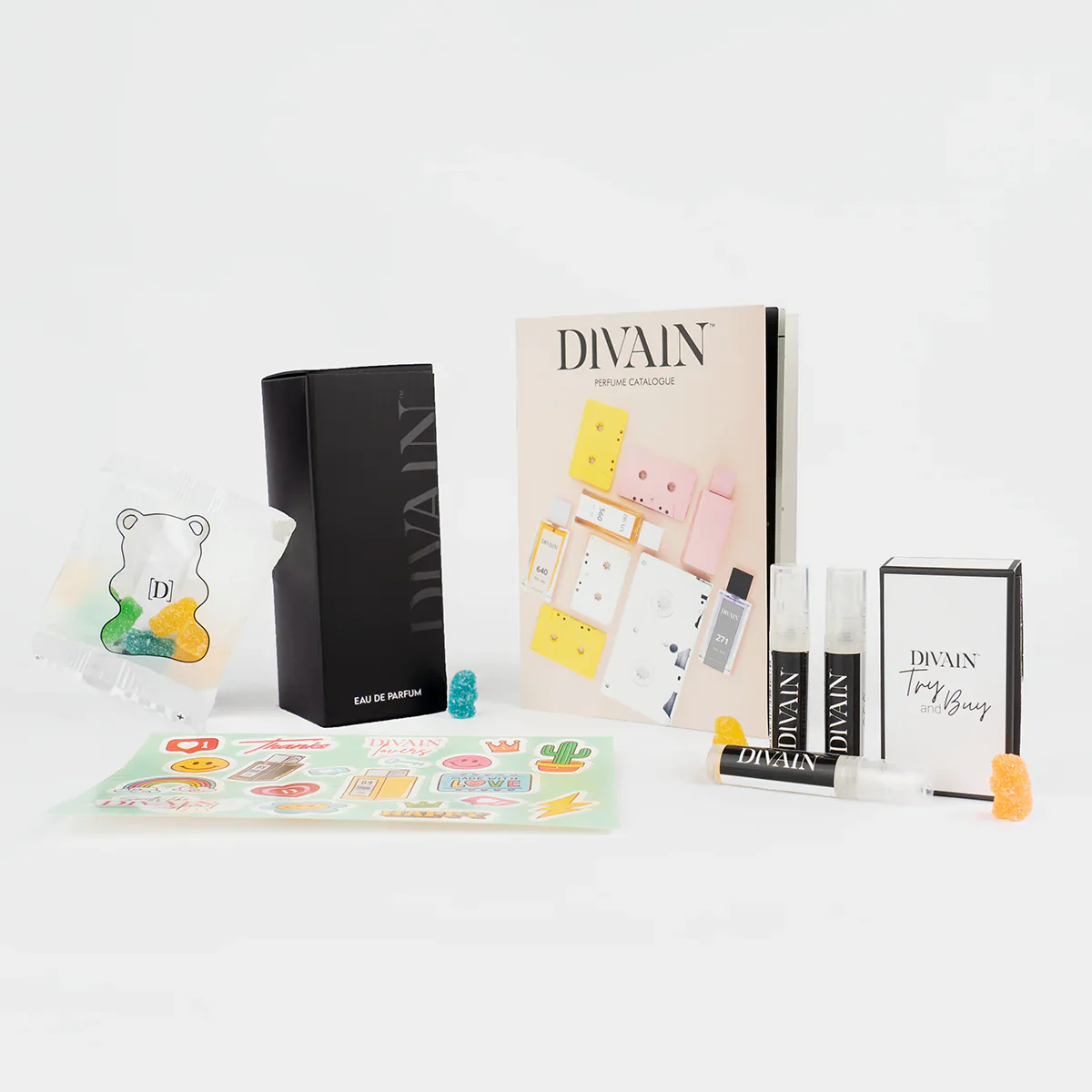 Paquet divain ouvert contenant le parfum divain-416, autocollants et bonbons
